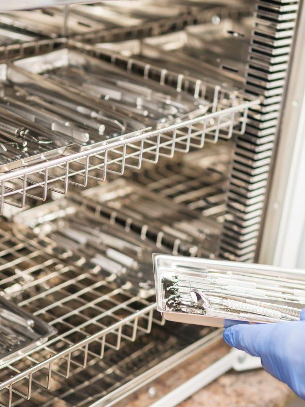 Hands Of The Dentist Load The Instrument Into The Sterilization Cabinet