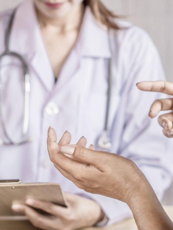 Female Patient Talking And Explaining About Health Problem To The Doctor At A Hospital