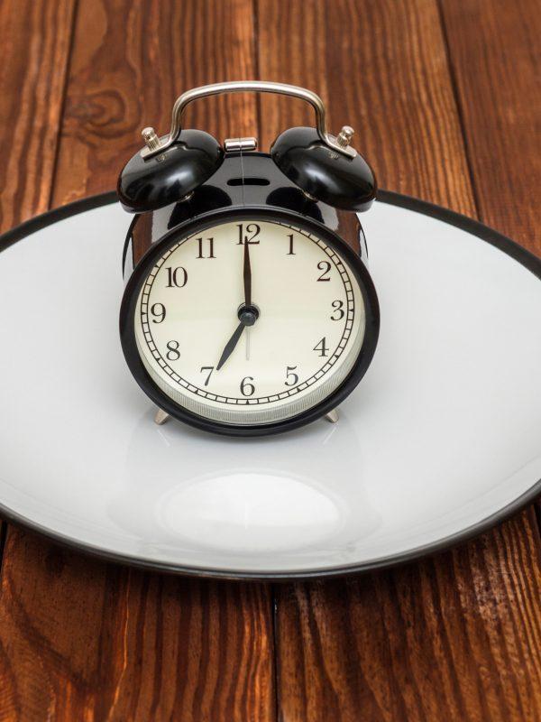 Alarm Clock On Plate With Knife And Fork On Wooden Background. W